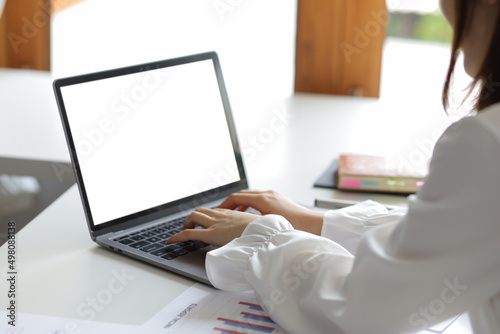 Thinking woman working on laptop with blank screen for copy space on office desk.