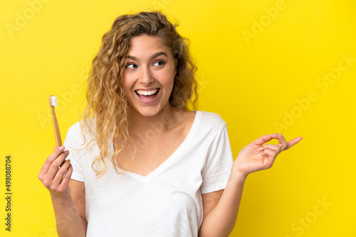 Young caucasian woman holding a brushing teeth isolated on yellow background intending to realizes the solution while lifting a finger up