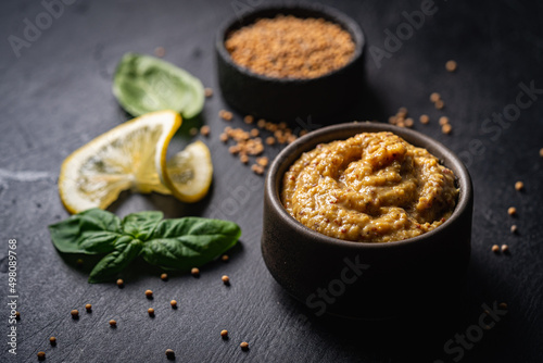 Fresh homemade organic dijon mustard in a bowl on black background, close up