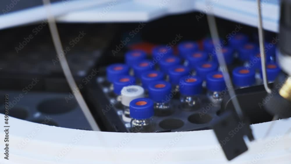 Laboratory assistant in rubber gloves puts vial with vaccine into HPLC Autosampler. Liquid chromatography at chemical laboratory extreme closeup Laboratory assistant in rubber gloves puts vial with vaccine into HPLC Autosampler. Liquid chromatography at chemical laboratory extreme closeup