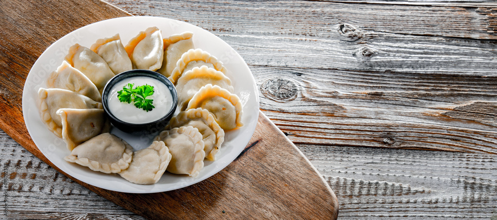 Composition with a plate of classic pierogies with sour cream Composition with a plate of classic pierogies with sour cream