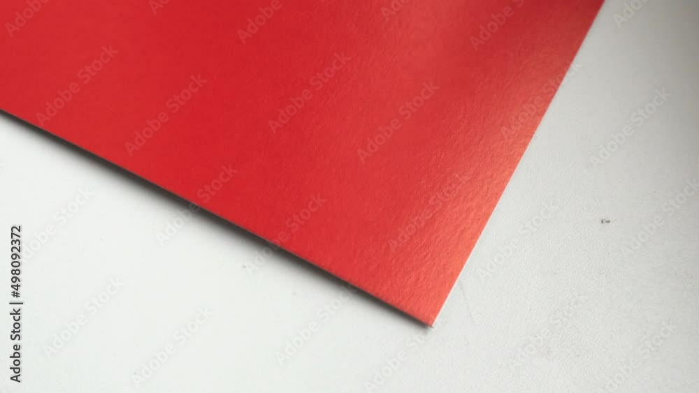 4k video, close-up, one sheet of red paper rotating on a white background, top view. 4k video, close-up, one sheet of red paper rotating on a white background, top view.