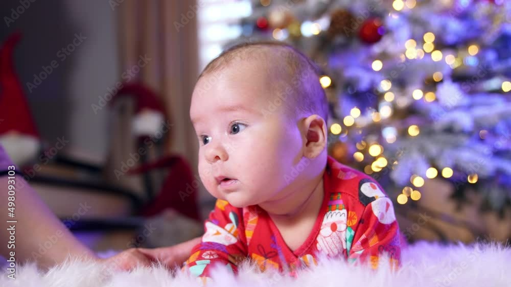 Beautiful Caucasian baby lies on the floor. Little boy is trying to hold his head and mommy supports the child. Beautiful Caucasian baby lies on the floor. Little boy is trying to hold his head and mommy supports the child.