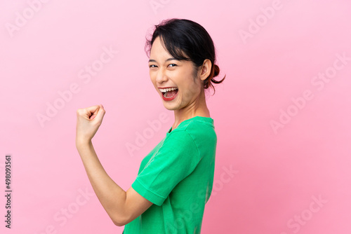 Young Vietnamese woman isolated on pink background celebrating a victory