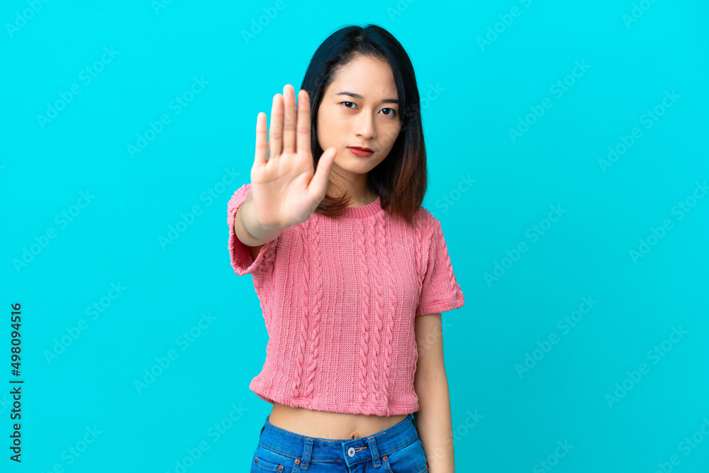 Young Vietnamese woman isolated on blue background making stop gesture Young Vietnamese woman isolated on blue background making stop gesture