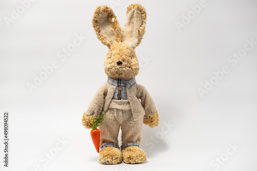 Easter Decorations Hare Rabbit of straw. Easter toy rabbit made of straw in a tuxedo, and with carrots in hand isolated on a white background