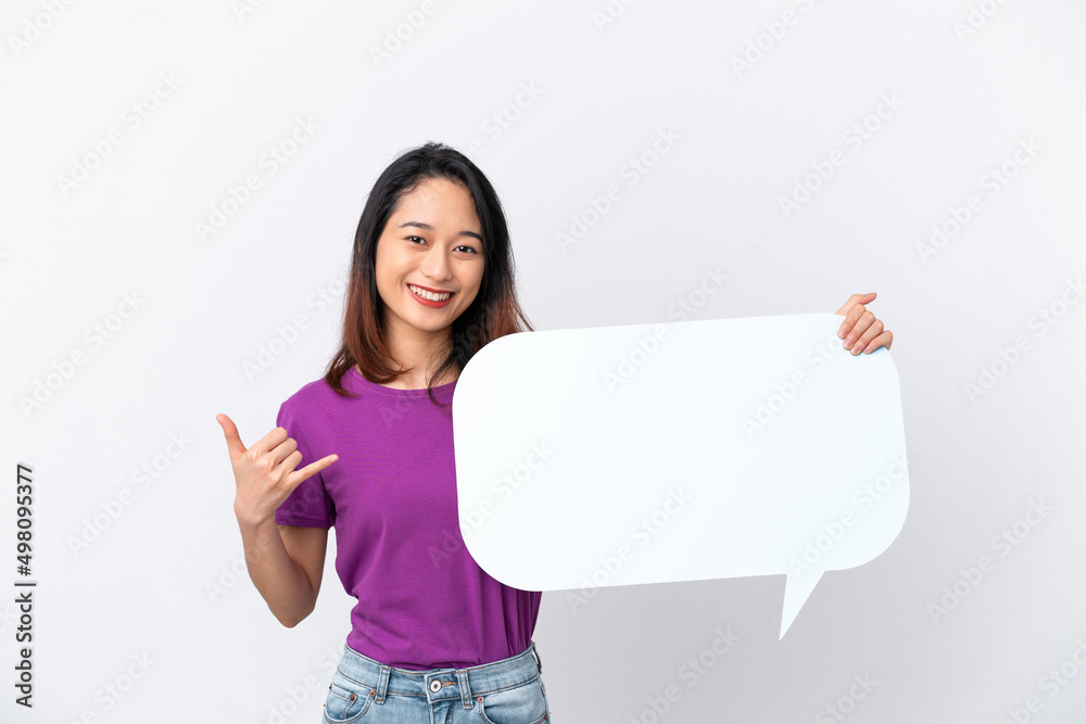 Young Vietnamese woman isolated on white background holding an empty speech bubble and doing phone gesture