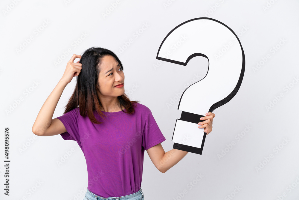 Young Vietnamese woman isolated on white background holding a question mark icon and having doubts Young Vietnamese woman isolated on white background holding a question mark icon and having doubts