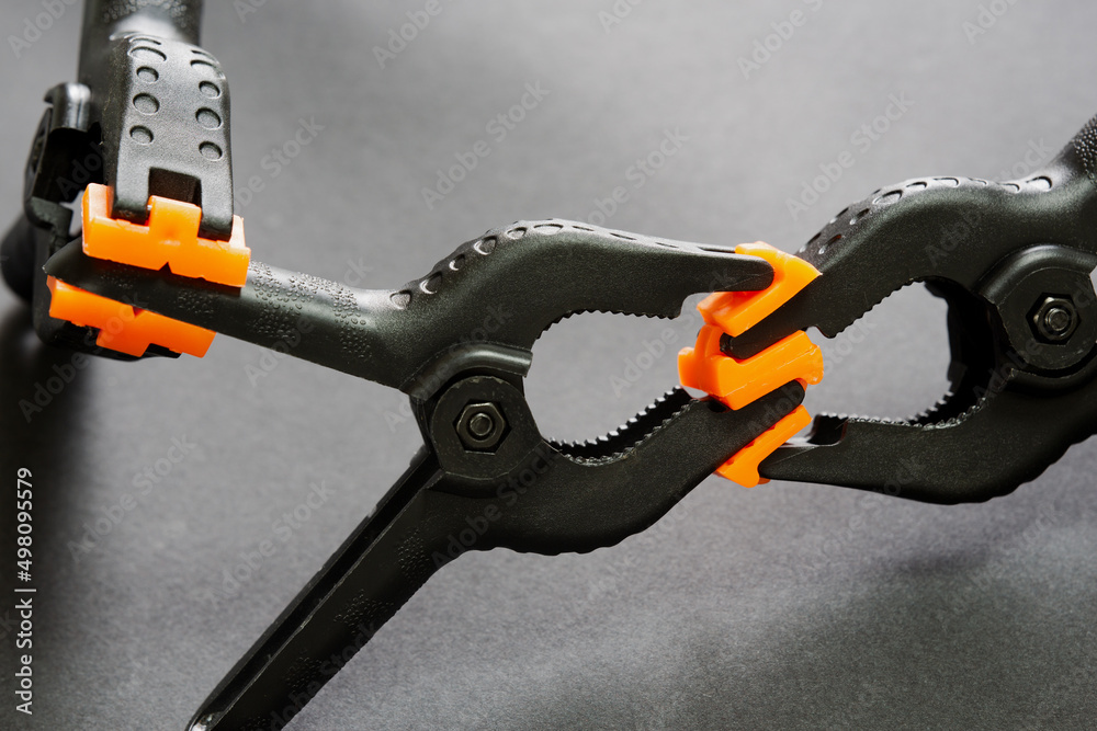 Naklejka premium Selective focus of plastic clamps holding each other on Black Isolated background. Compressing, holding, fixing concept. Abstract concept of deception, addiction, struggle, hindrance, pursuit.
