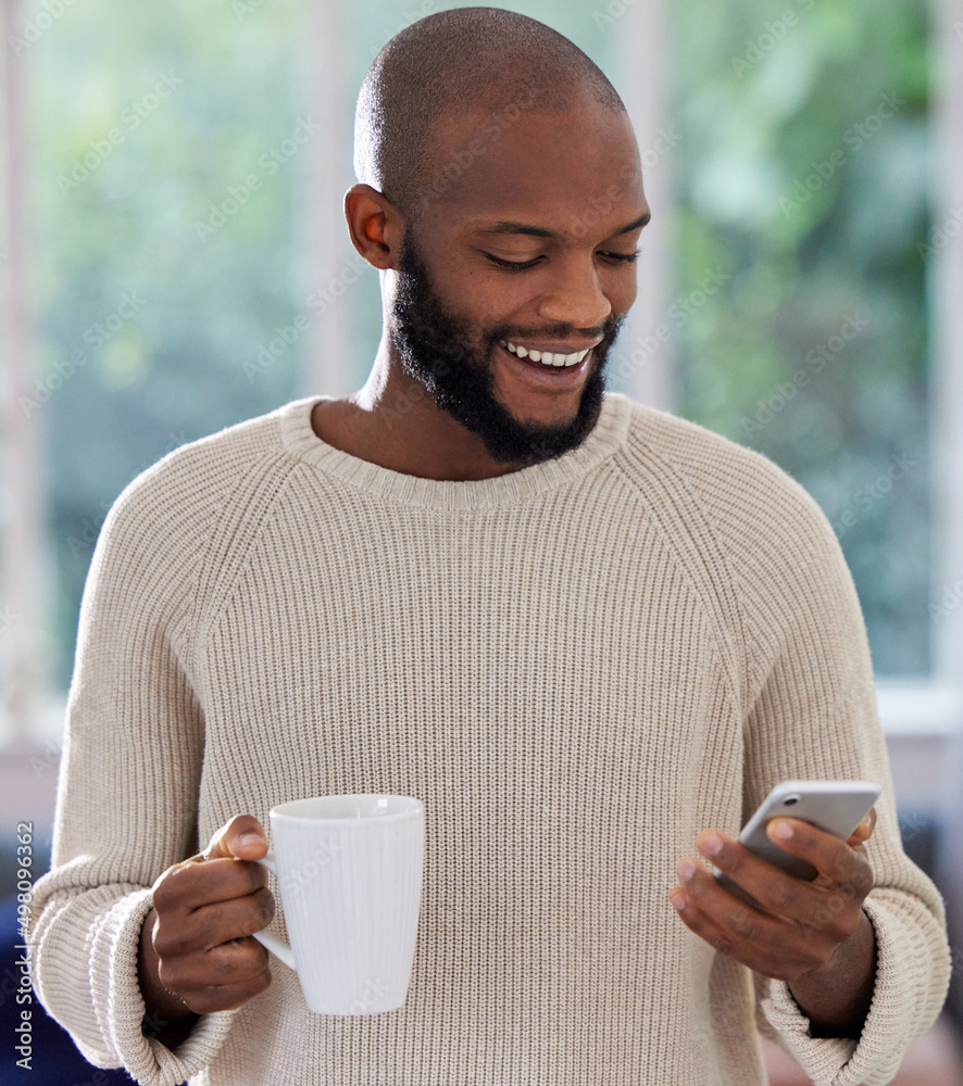 This app is so convenient. Shot of a young man drinking coffee while using a phone at home. This app is so convenient. Shot of a young man drinking coffee while using a phone at home.