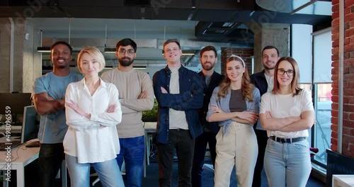 Portrait shot of mixed-races people standing in office, smiling to camera and crossing hands in front of them. Multiethnic men and women. Young group of IT startup. photo