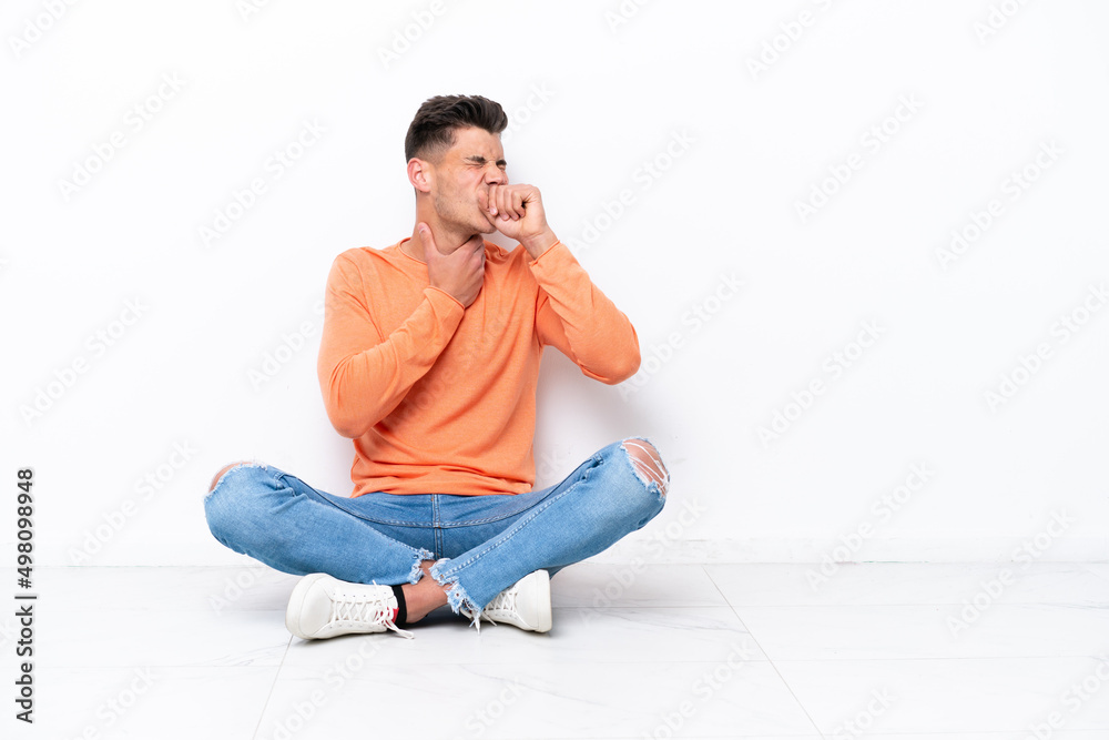 Young man sitting on the floor isolated on white background is suffering with cough and feeling bad Young man sitting on the floor isolated on white background is suffering with cough and feeling bad