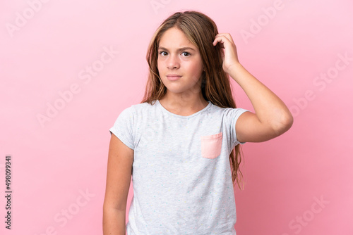 Little caucasian girl isolated on pink background having doubts
