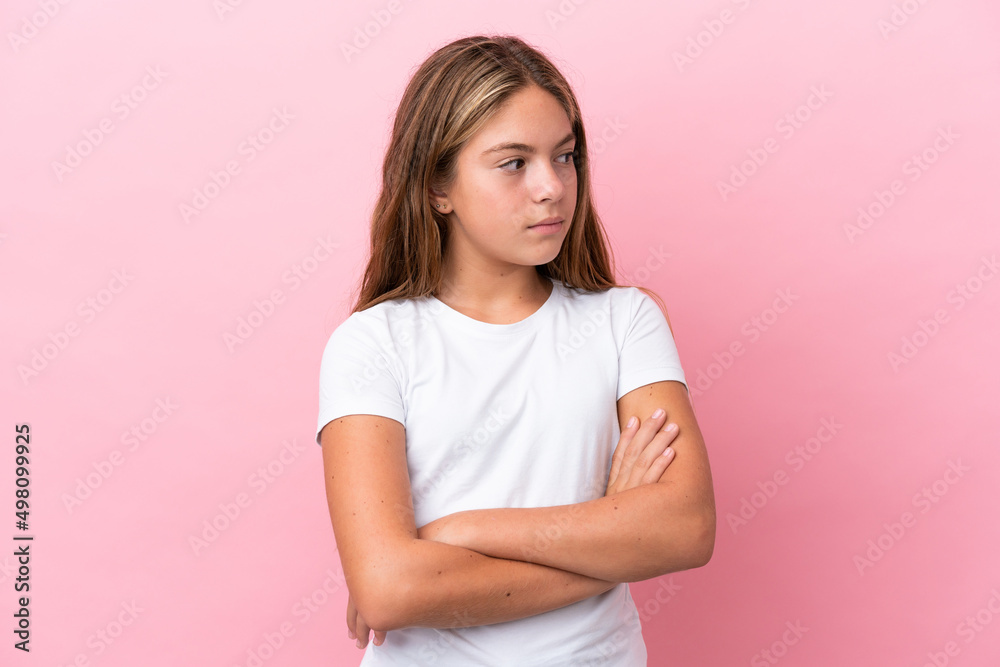 Little caucasian girl isolated on pink background keeping the arms crossed