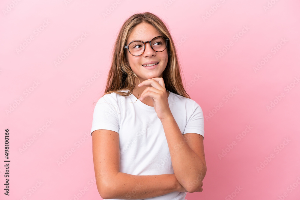Little caucasian girl isolated on pink background With glasses and thinking while looking up