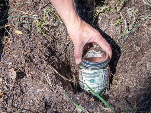 Φωτογραφία Burying a jar of money in the garden as savings, retirement or college fund concept