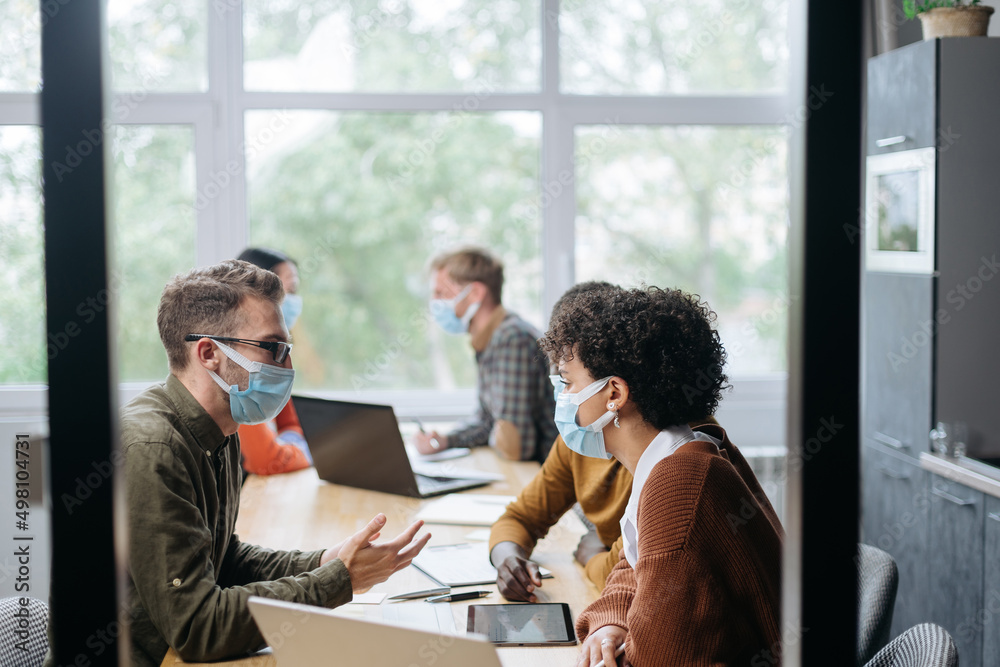 employees in protective masks work in the hall of the coworking