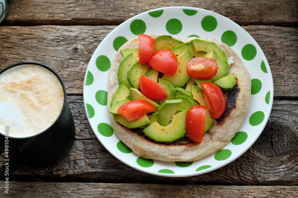 Flatbread with avocado and tomato. Wooden background, top view Flatbread with avocado and tomato. Wooden background, top view
