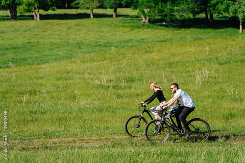 Long shot of a couple traveling on bikes in the countryside. Side view.