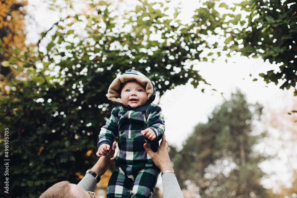 Adorable baby in warm overall with hood sitting on foliage. Adorable baby in warm overall with hood sitting on foliage.