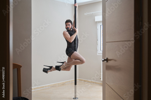 Young man wearing make up, fishnet stockings and heels pole dancing. Gender identity. © Ladanifer