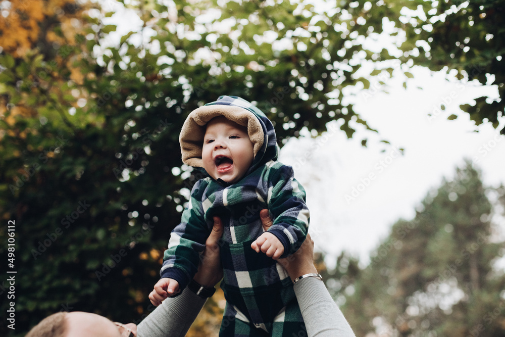 Adorable baby in warm overall with hood sitting on foliage. Adorable baby in warm overall with hood sitting on foliage.