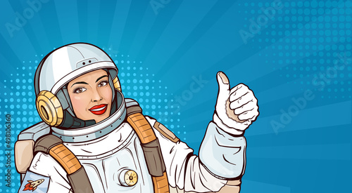 Pop art astronaut girl in space suit showing thumb up or like gesture. Smiling woman cosmonaut in helmet and uniform for exploration demonstrating approval sign on blue halftone background.