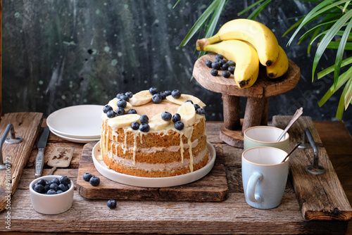 Banana cake with blueberries and white chocolate. Wooden background, side view