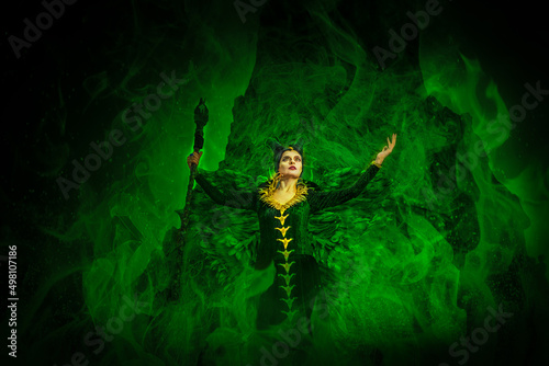 MALEFIC COSPLAY. PORTRAIT  DARK CHARACTER WITH SHARP HORNS AND STRONG WINGS. EVIL FAIRY IN BLACK DRESS. GREEN COLOR.