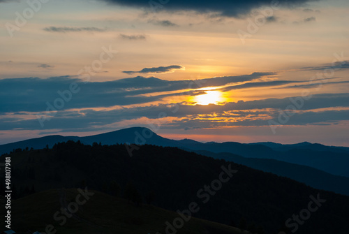 Carpathian mountains at sunset. Evening sky with clouds. Contrasting mountain landscape. Distant mountain peak. Morning or evening in the mountains