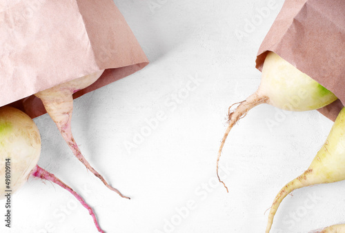 Margelan and watermelon radish in paper bags on the white table. Farm organic vegetable variations photo