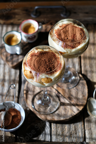 Portioned tiramisu in a glass. Wooden background, side view