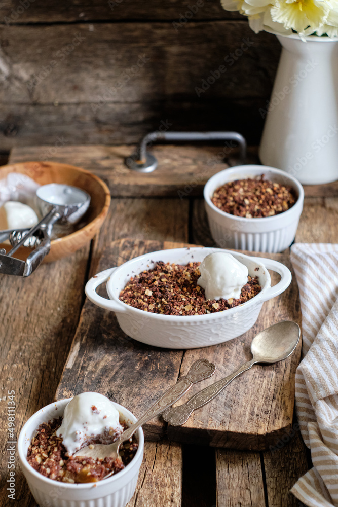 Crumble with apple and chocolate. Narcissus, ice cream, wood background, side view, vensa. Crumble with apple and chocolate. Narcissus, ice cream, wood background, side view, vensa.