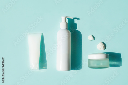 Eco-friendly cosmetics for face and body skin care. White tube, bottle and jar of cream on a blue background. Hard Shadows.