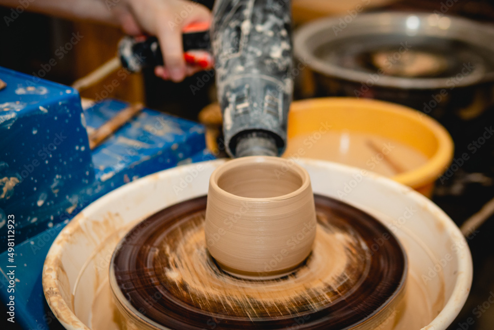 Obraz premium Potter working on potters wheel with clay. Process of making ceramic tableware in pottery workshop. Handicraft and art concept.