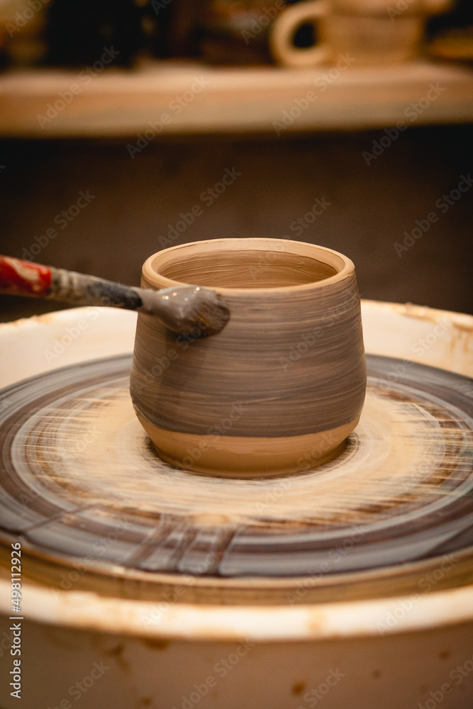 Potter working on potters wheel with clay. Process of making ceramic tableware in pottery workshop. Handicraft and art concept. Potter working on potters wheel with clay. Process of making ceramic tableware in pottery workshop. Handicraft and art concept.