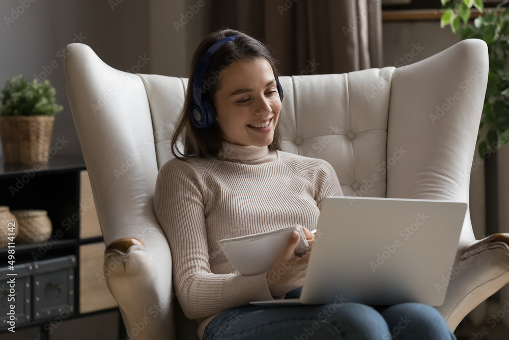 Positive happy gen Z student girl wearing headphones, talking to ...