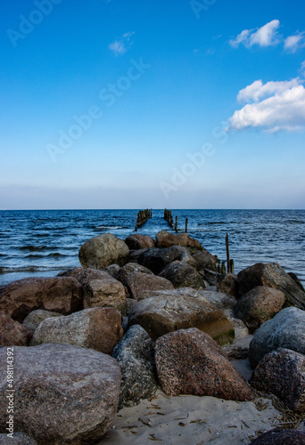 Old wooden poles on the shores of the Baltic Sea with stones in the foreground
