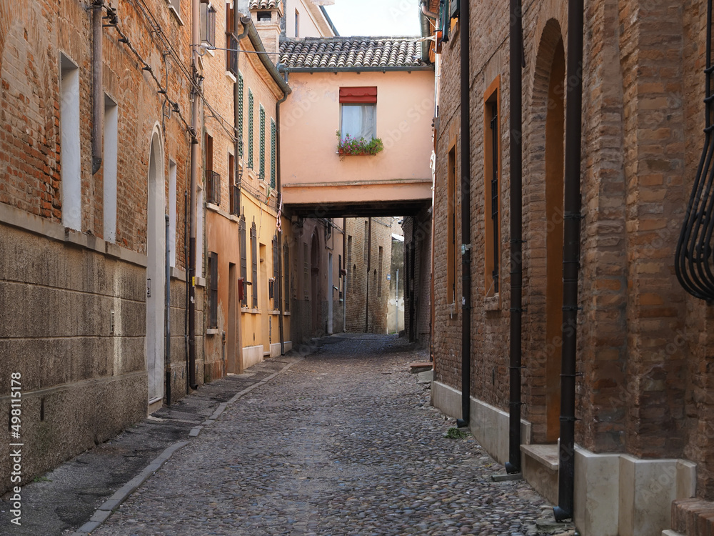 Ferrara, Italy. Downtown, medieval cobbled street with archway.