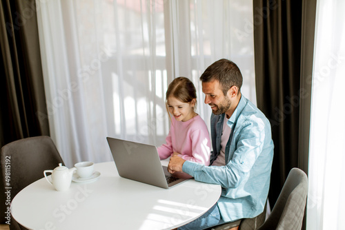 Father and daughter using laptop computer together