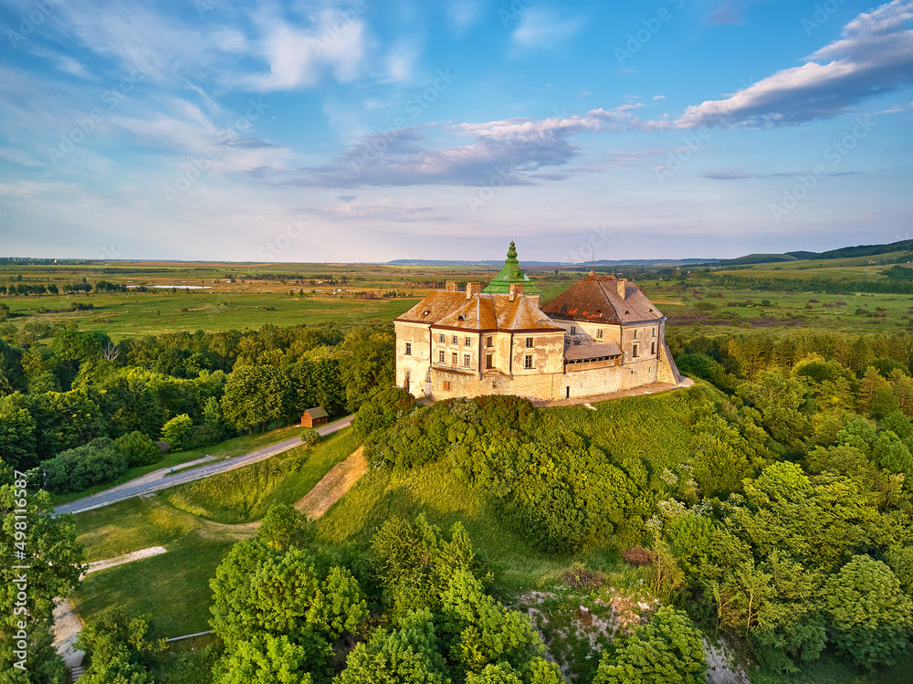 Medieval Olesko Palace aerial view. Picturesque sunny scene, green spring trees. Summer park on hills.