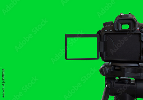 Dslr camera with empty screen on the tripod, isolated on green background. Green screen camera.