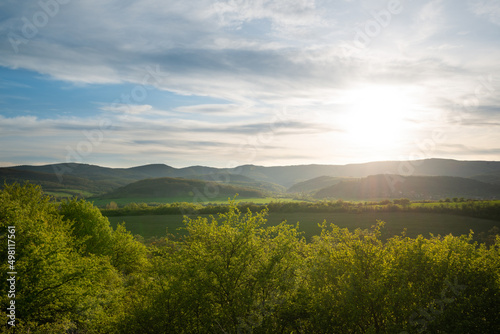 Beautiful green mountain landscape with sun and sun rays over the hills. © Jordanj