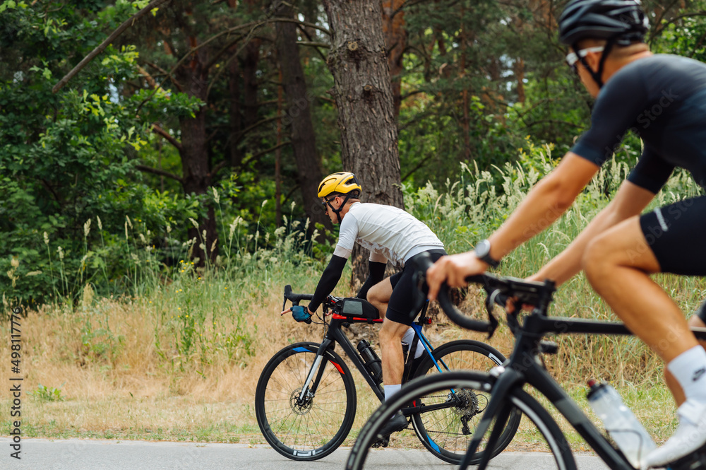 Bicycle riders Men cyclists train outside the city in the woods on ...