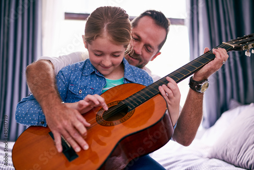 Musical bonding. Cropped shot of a father and daughter playing the guitar together at home.