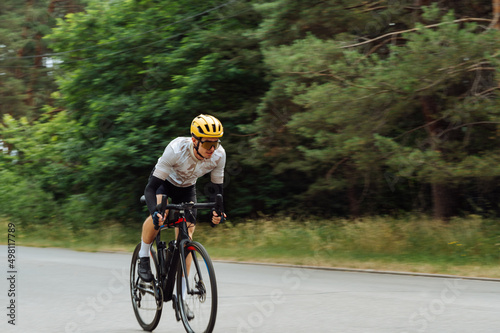Blurred photo in motion of a professional cyclist in training, quickly rides on an asphalt road in the woods outside the city