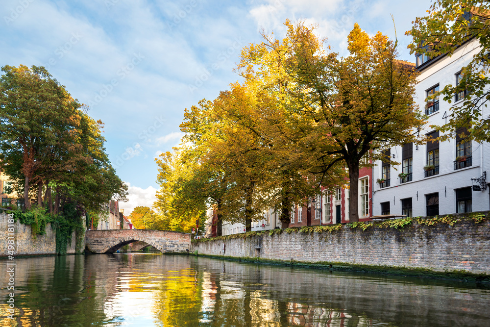 Historical canal in Bruges, Belgium. Beautiful reflection of autumn yellow trees in the water.