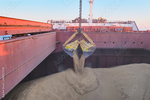 Loading of wheat, barley in bulk using steel grab into cargo hold of bulk carrier, cargo ship photo