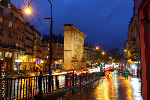 Porte Saint-Denis at rainy night . It is a Parisian monument located in the 10th arrondissement of Paris, France.