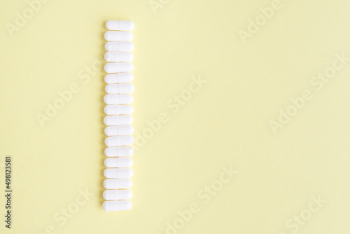 White capsules on a yellow background. Medical background with copy space for text.